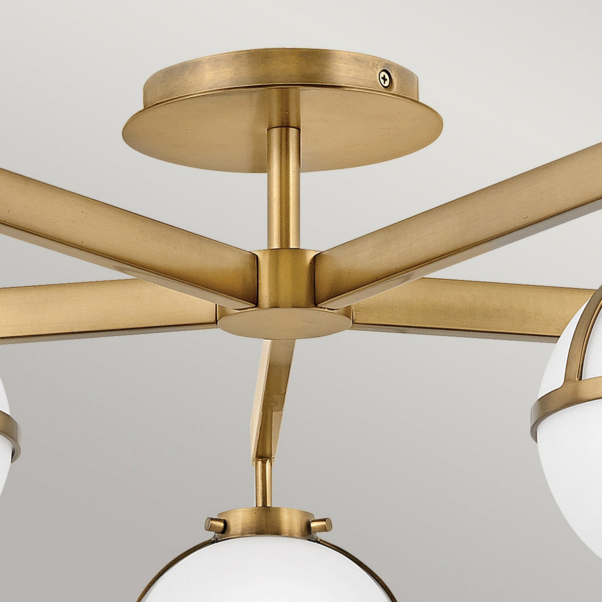 Close-up of the Hollis 5 Light Semi Flush in Heritage Brass, showcasing its multiple arms radiating from a central base. Each arm supports an exquisite opal etched glass shade, blending modern elegance with refinement against a light gray background.