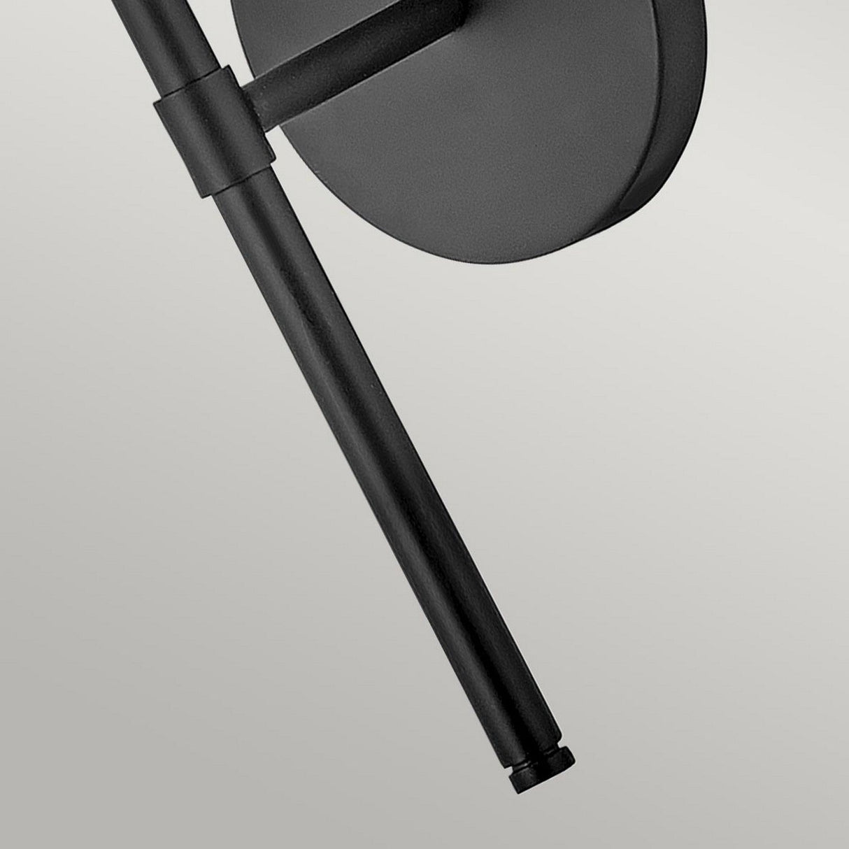 Close-up of the Hollis 1 Light Wall Light in black, mounted against a light gray background. The fixture attaches to a circular base with an opal glass finish, showcasing its sleek and minimalist design that highlights modern decor elements.