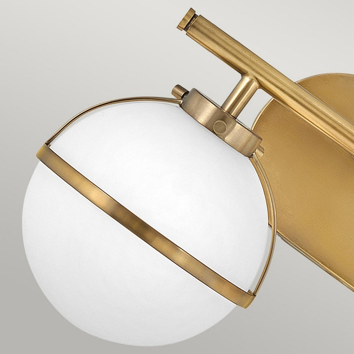 The Hollis 2 Light Wall Light - Heritage Brass With Opal Glass showcases a contemporary style with an opal glass globe set in heritage brass. This sophisticated fixture is attached to a brass arm and backplate, making it an ideal match for any neutral setting.