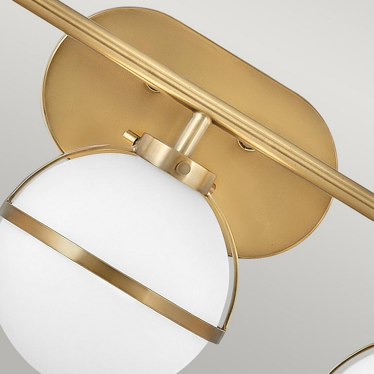 Detailed view of the Hollis 3 Light Wall Light, featuring an opal glass shade and heritage brass accents, complemented by a matching brass mounting bracket against a neutral backdrop.