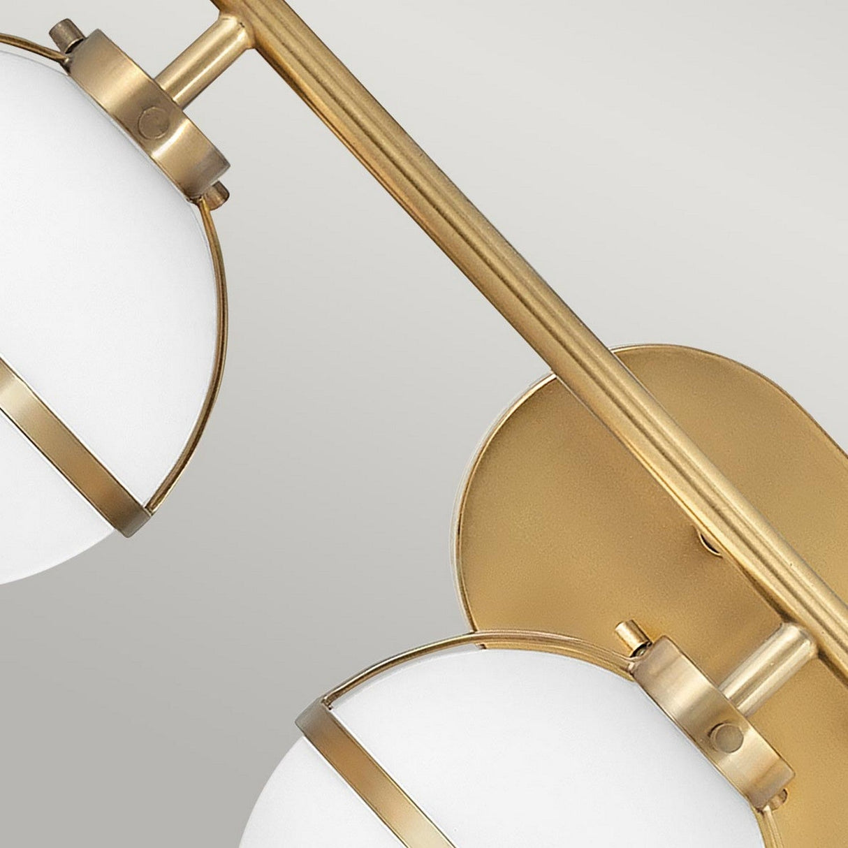 Close-up of the Hollis 3 Light Wall Light, featuring two spherical opal glass lampshades with gold accents, elegantly mounted on a Heritage Brass fixture against a light gray background.