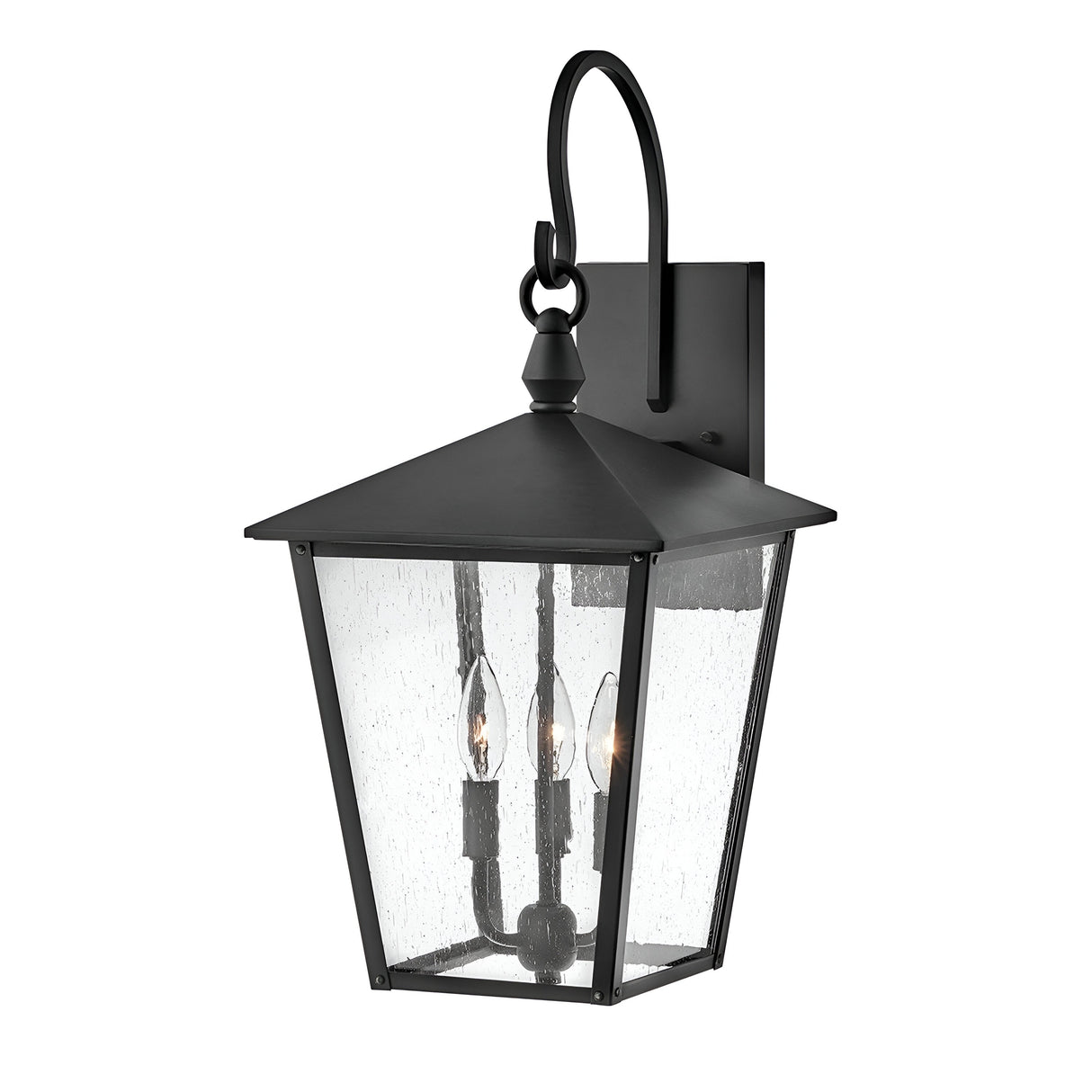 The Huntersfield Outdoor 3 Light Large Wall Lantern - Black blends traditional aesthetics with its black finish, square base, and clear seeded glass panels. Ideal for outdoor decor, it includes two candle-style lights and a refined arched mounting bracket.