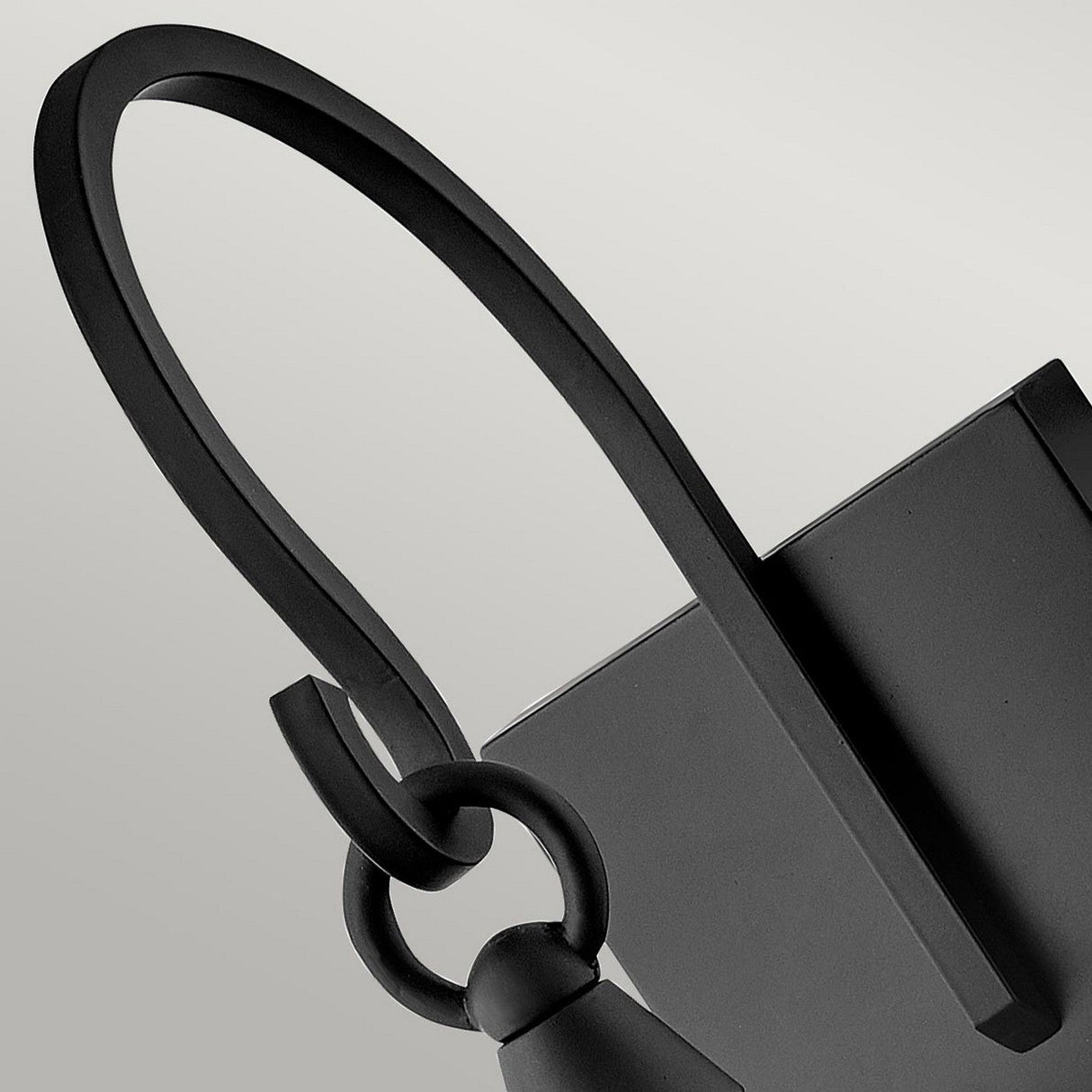 Close-up of a modern, minimalist black wall hook with a sleek, curved design. Echoing traditional aesthetics, the hook features interlocking loops and a geometric form, set against a plain grey background. Perfect for complementing your Huntersfield Outdoor 3 Light Large Wall Lantern - Black or enhancing outdoor decor.