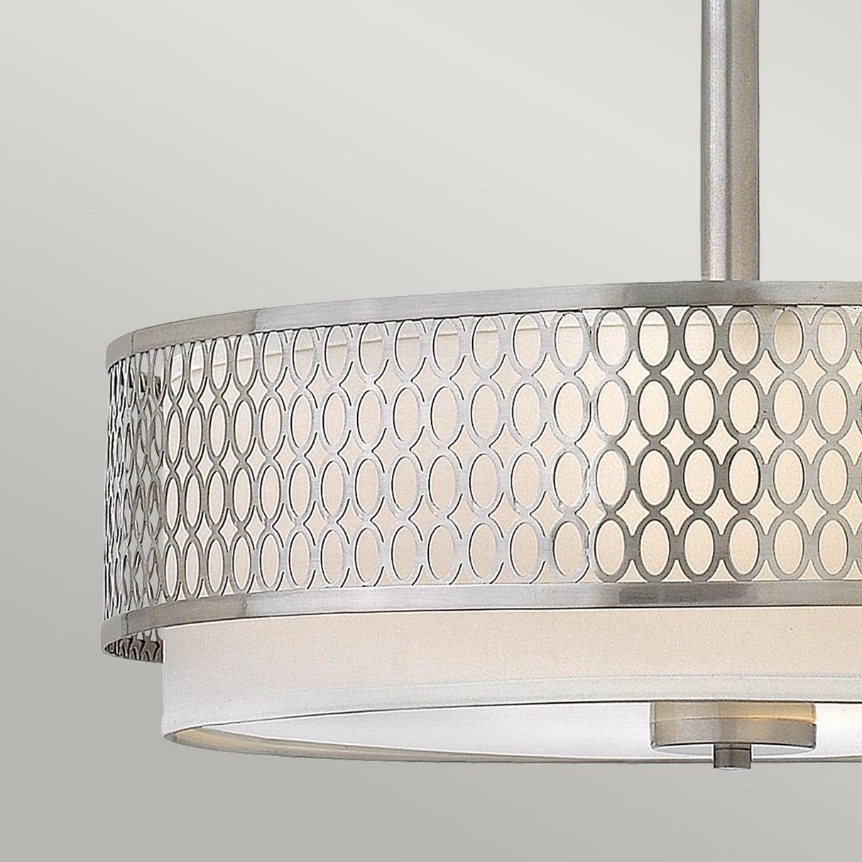 The Jules 3 Light Pendant / Semi-Flush in a Brushed Nickel finish exudes modern elegance with its metallic drum-shaped shade adorned with an overlapping circle pattern. Its white diffuser softens the light, creating a sleek, contemporary design that makes it a stunning addition against any neutral background.