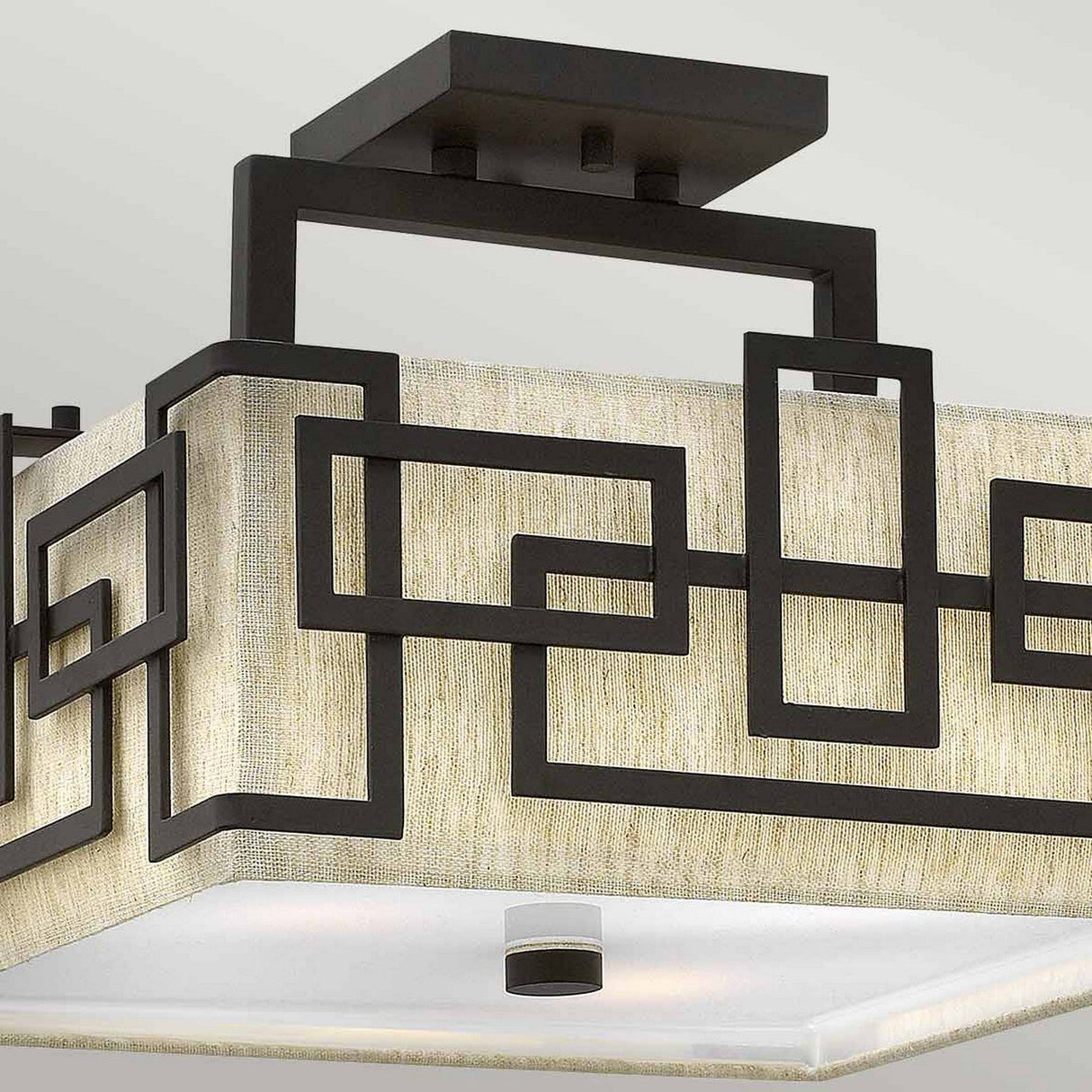 The Lanza 3 Light Semi Flush - Oil Rubbed Bronze is a modern ceiling light fixture that features geometric metal outlines with an oil-rubbed bronze finish set against a beige fabric background, showcasing minimalist and contemporary design elements.