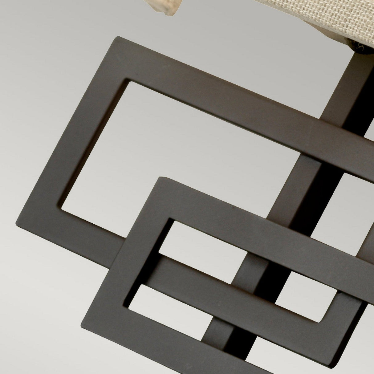 Here is a new version of the sentence using the provided product data:
Close-up of the Lanza 2 Light Wall Light, featuring intersecting rectangular shapes and geometric detailing against a neutral background. Its oil-rubbed bronze finish enhances its modern, abstract design with rustic elegance.