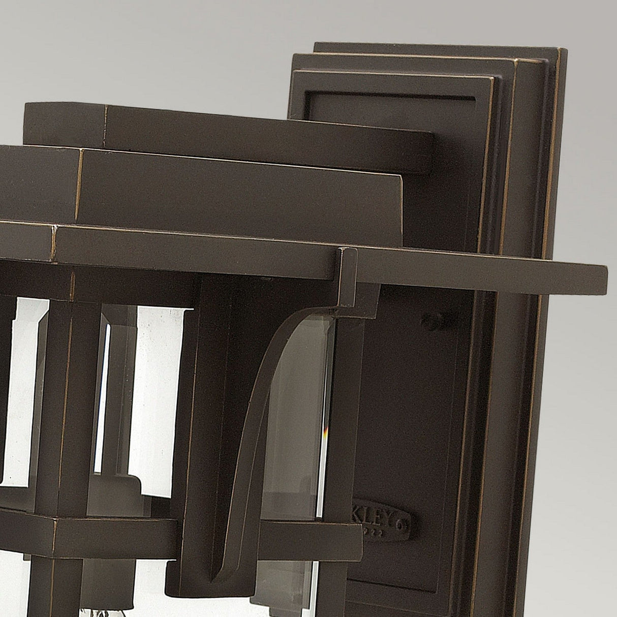 Close-up of the Manhattan Outdoor 1 Light Large Wall Lantern in oil rubbed bronze, showcasing its clear glass panels and geometric design elements, mounted on a wall.