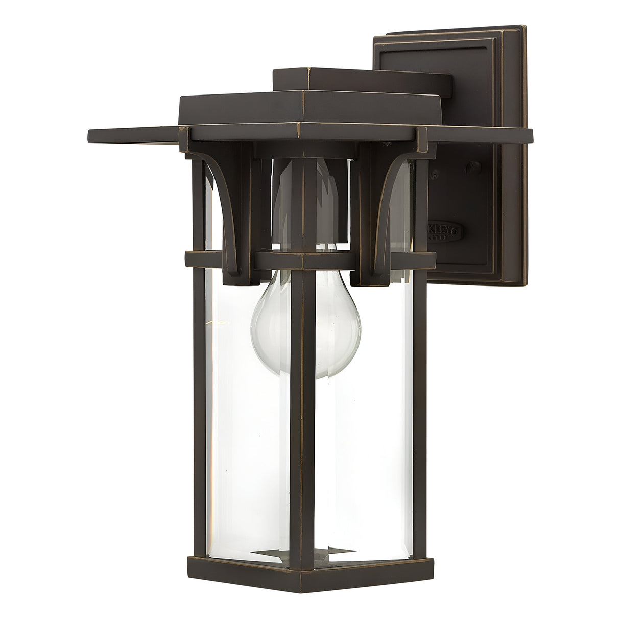 The Manhattan Outdoor 1 Light Small Wall Lantern features a vintage design with its oil-rubbed bronze finish. Its rectangular frame and clear glass panels showcase a visible bulb inside, while the modern geometric lines enhance its square backplate.
