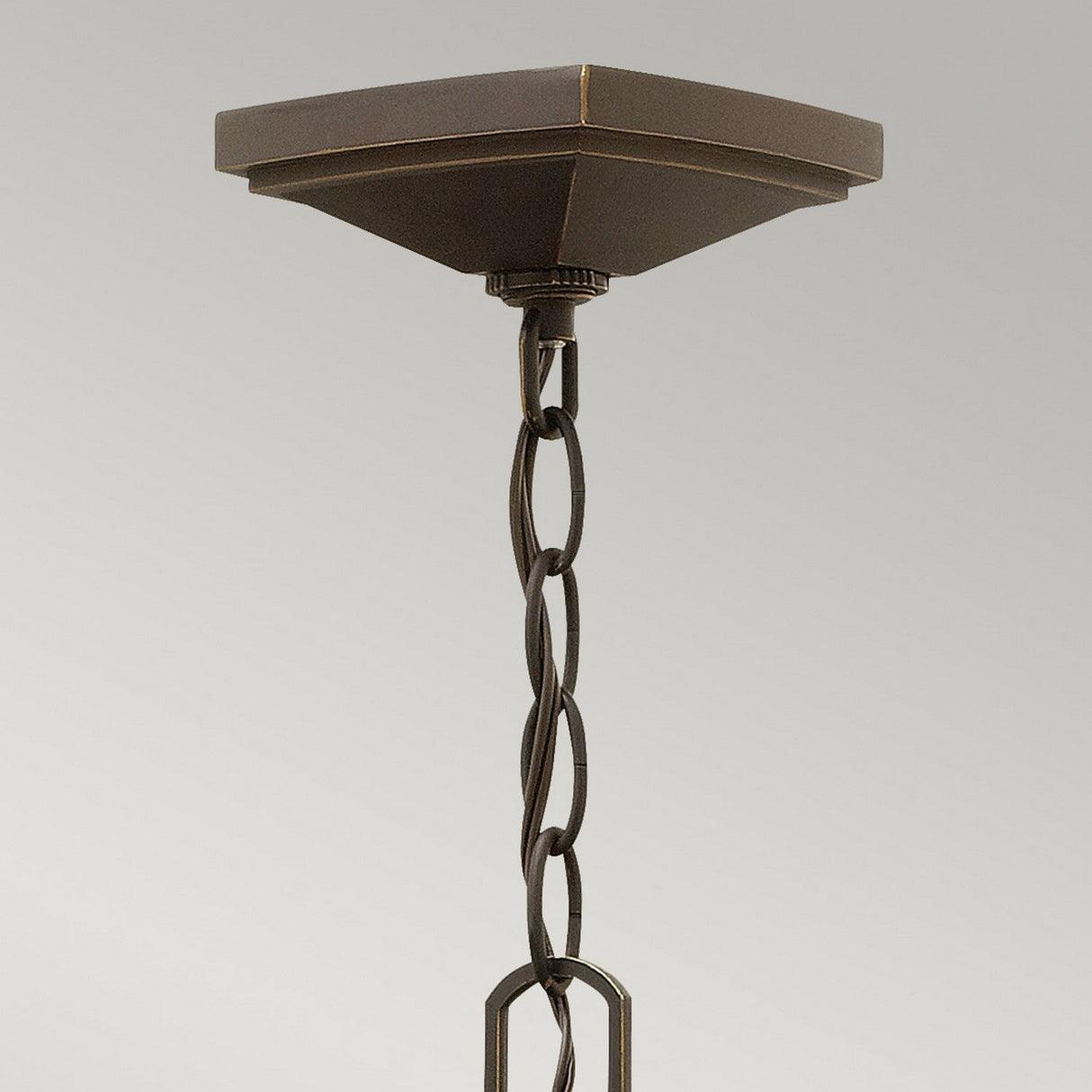 A close-up of the Manhattan Outdoor 1 Light Chain Pendant in an oil rubbed bronze finish, showcasing its twisted chain against a gray background. The square canopy exudes a smooth, dark allure reminiscent of vintage train station lantern design.