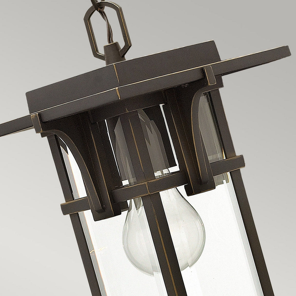 A detailed look at the Manhattan Outdoor 1 Light Chain Pendant reveals its vintage-style charm, evoking classic train station designs. It features a clear glass panel and an exposed bulb, complemented by a metal fixture in an oil rubbed bronze finish with defined edges. Suspended by a chain, it serves as an ideal outdoor light fixture.