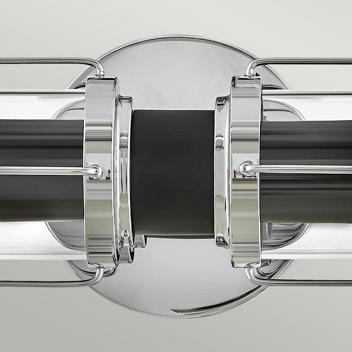The Masthead 2 Light Wall Light in polished chrome and black beautifully highlights nautical charm with its cylindrical glass casing and polished chrome finishes. It features a symmetrical design and sleek lines set against a neutral backdrop, adding an air of elegance and style.