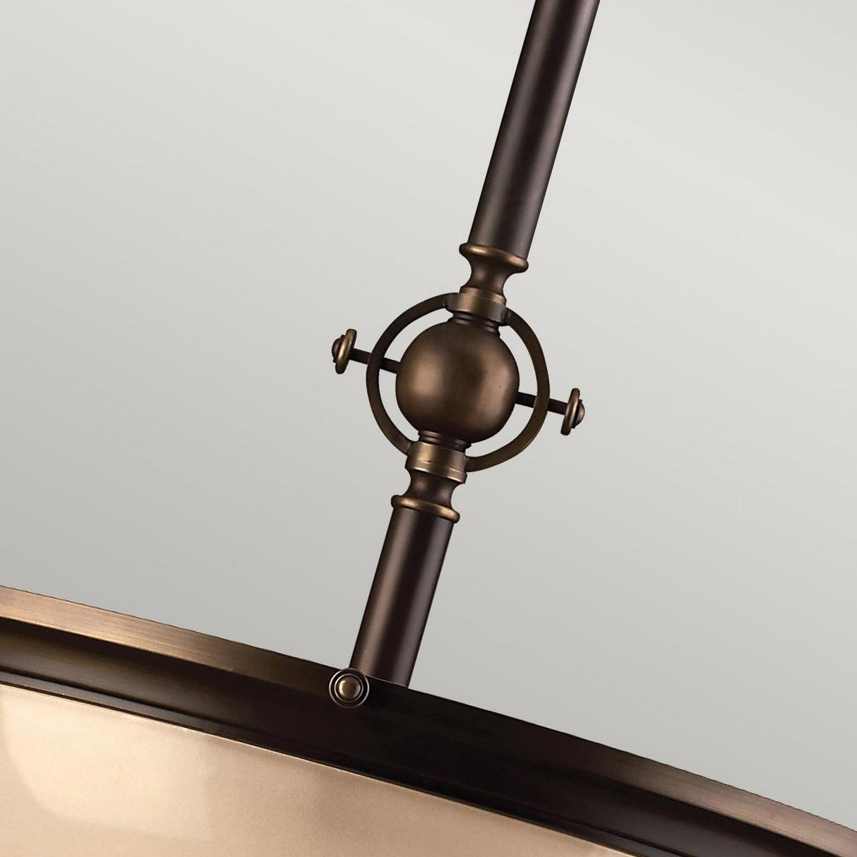 Close-up of the Mayflower 3 Light Pendant - Bronze, showcasing its decorative metal structure with a circular design and sleek bronze finish. It includes screws and a cylindrical rod with adjustable height, set against a neutral light gray background.