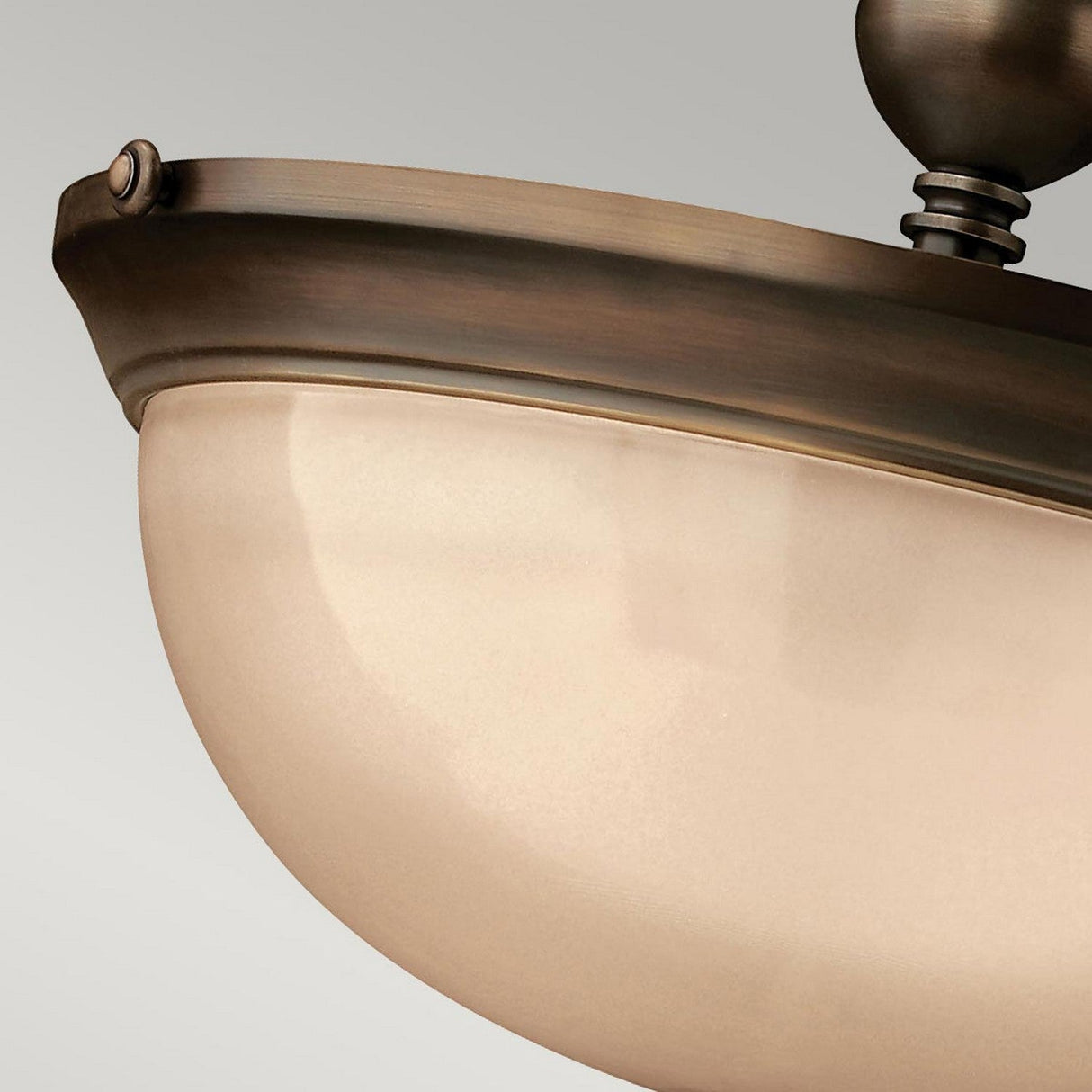 Close-up of the Mayflower 3 Light Semi Flush - Bronze ceiling fixture with frosted glass shades, mounted on a neutral-colored wall. The design showcases classic curves and detailing that harmonize beautifully with its etched amber glass shades.