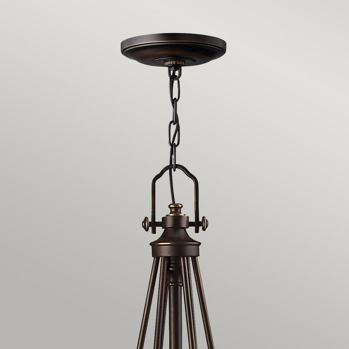 The Mayflower 6 Light Chandelier - Bronze gracefully hangs from the ceiling with its chain suspension, featuring a minimalist modern design. Its polished bronze finish harmonizes with the neutral backdrop, and the etched amber glass shades bring warmth to this exquisite chandelier.