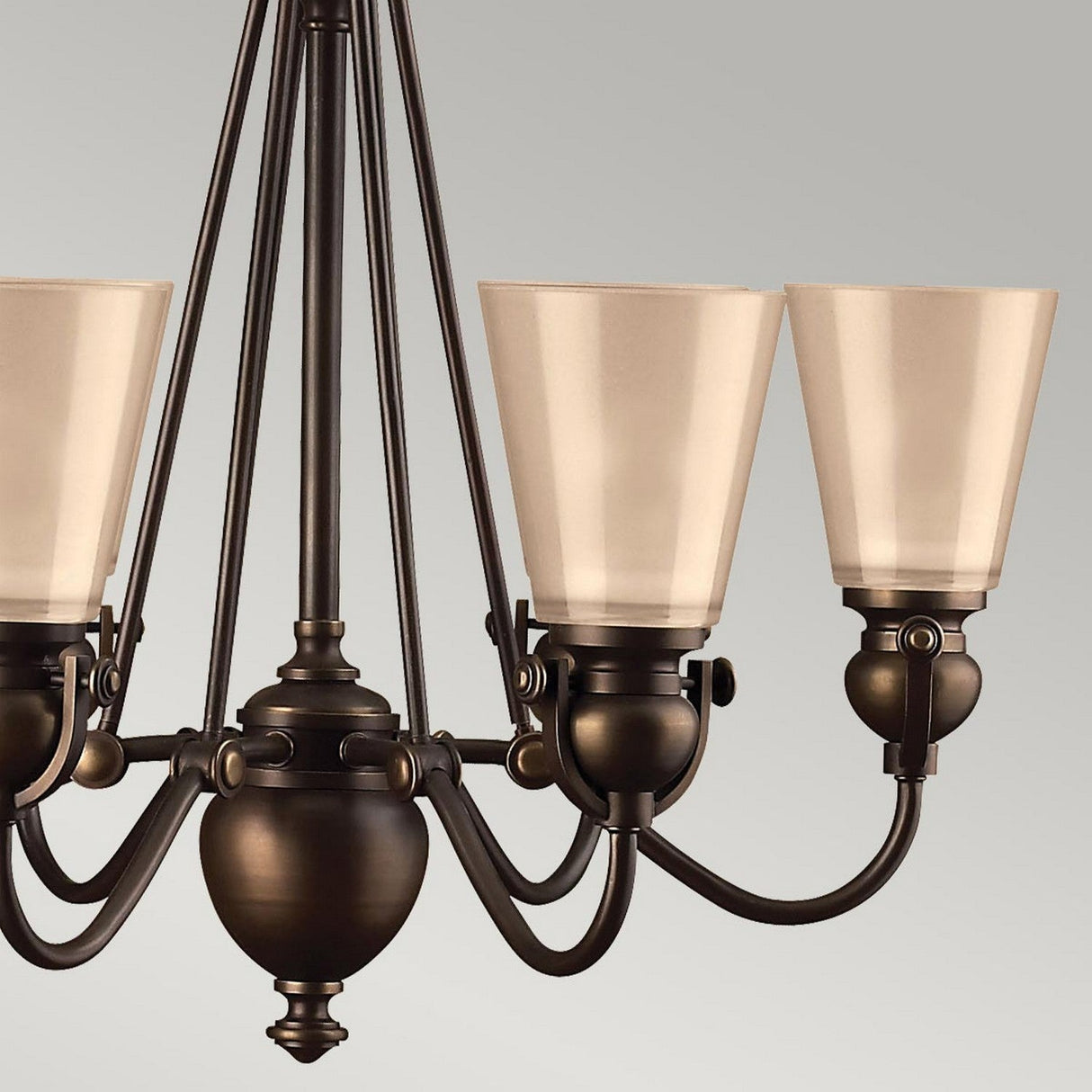 A close-up of the Mayflower 6 Light Chandelier - Bronze features etched amber glass shades and is suspended by multiple rods. This elegant fixture, with its classic design and matte finish, stands out beautifully against a neutral gray background.