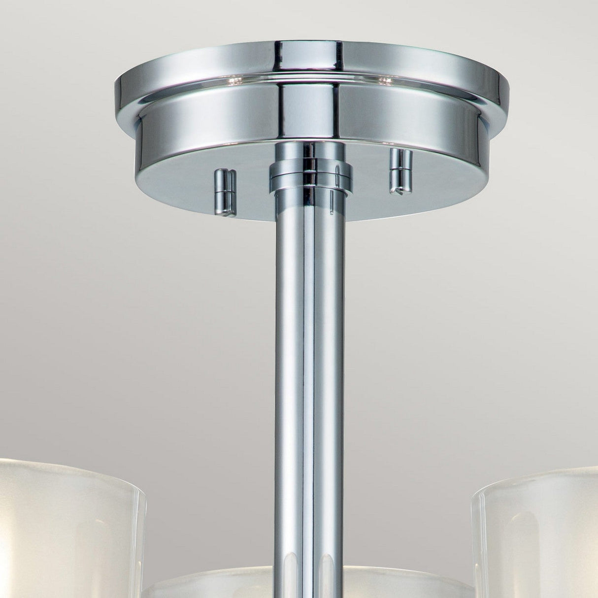 Close-up of the Meridian 3 Light Semi Flush - Polished Chrome ceiling light fixture, featuring cylindrical glass shades that accentuate its sleek metallic pole and circular base against a plain background. This design promotes energy efficiency while maintaining an elegant aesthetic.