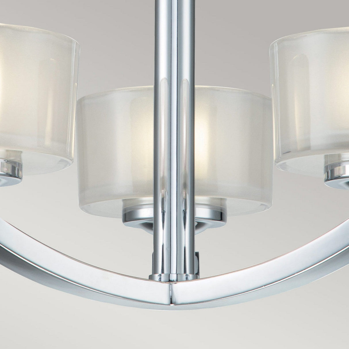 A close-up of the Meridian 3 Light Semi Flush fixture showcases its polished chrome finish, featuring three cylindrical glass shades that diffuse the light softly. Designed with a semi-flush mount, this piece emphasizes energy efficiency while offering a minimalist and contemporary aesthetic.