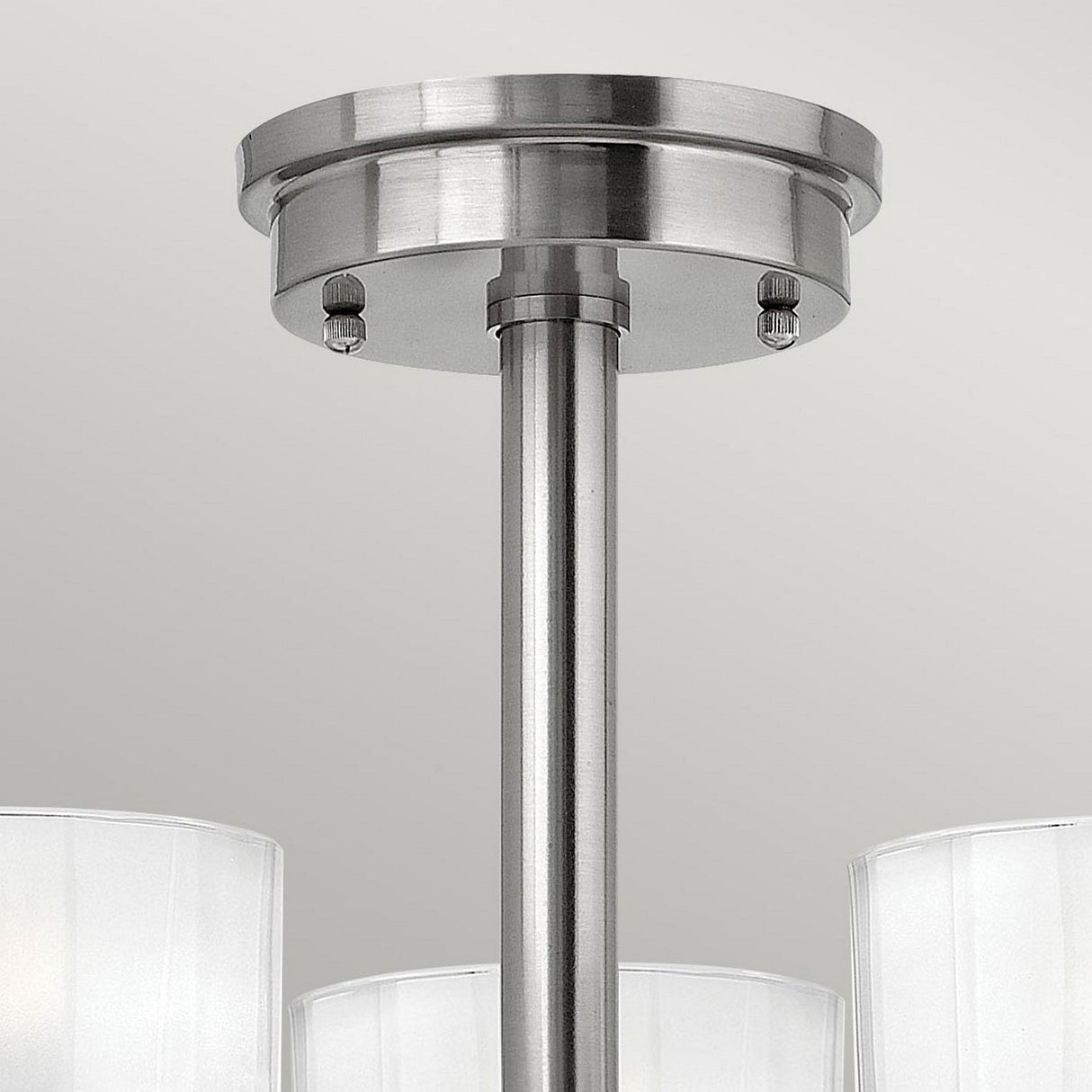 Close-up of the Meridian 3 Light Semi Flush in a brushed nickel finish featuring a metallic rod and base. This modern ceiling light fixture has three frosted white glass shades that are partially visible at the bottom, offering a sleek and energy-efficient look against a light gray background.