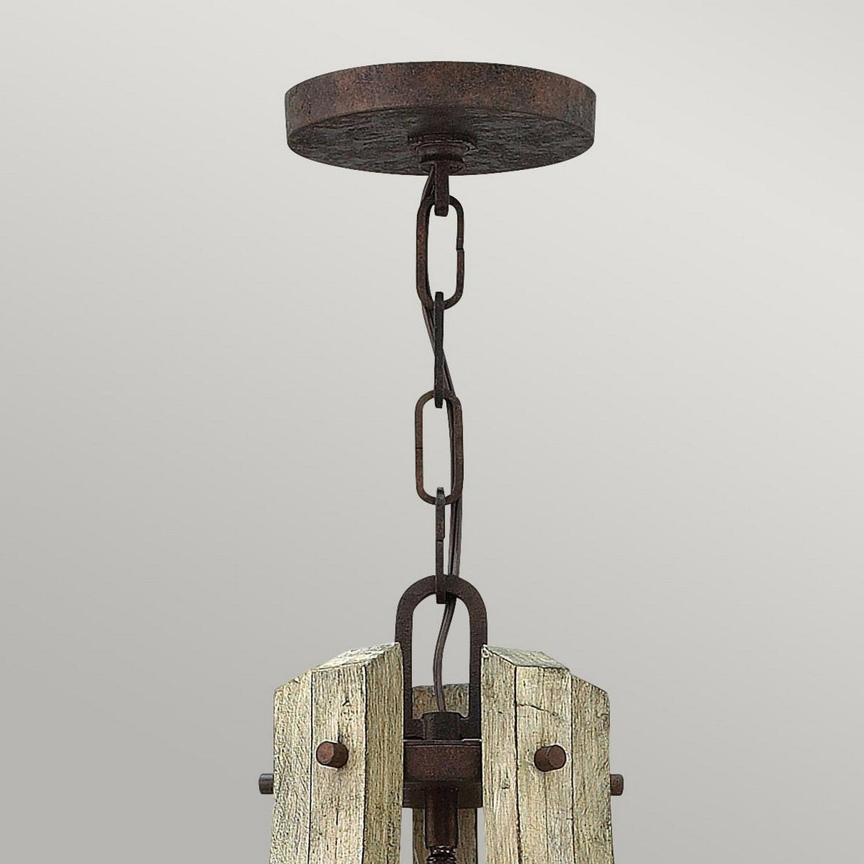 The Middlefield 5 Light Chandelier - Iron Rust exudes rustic charm with a weathered wooden frame and metal chains in an iron rust finish, hanging elegantly from a round ceiling mount against a neutral backdrop. Its vintage design makes it an eye-catching centerpiece in any room.