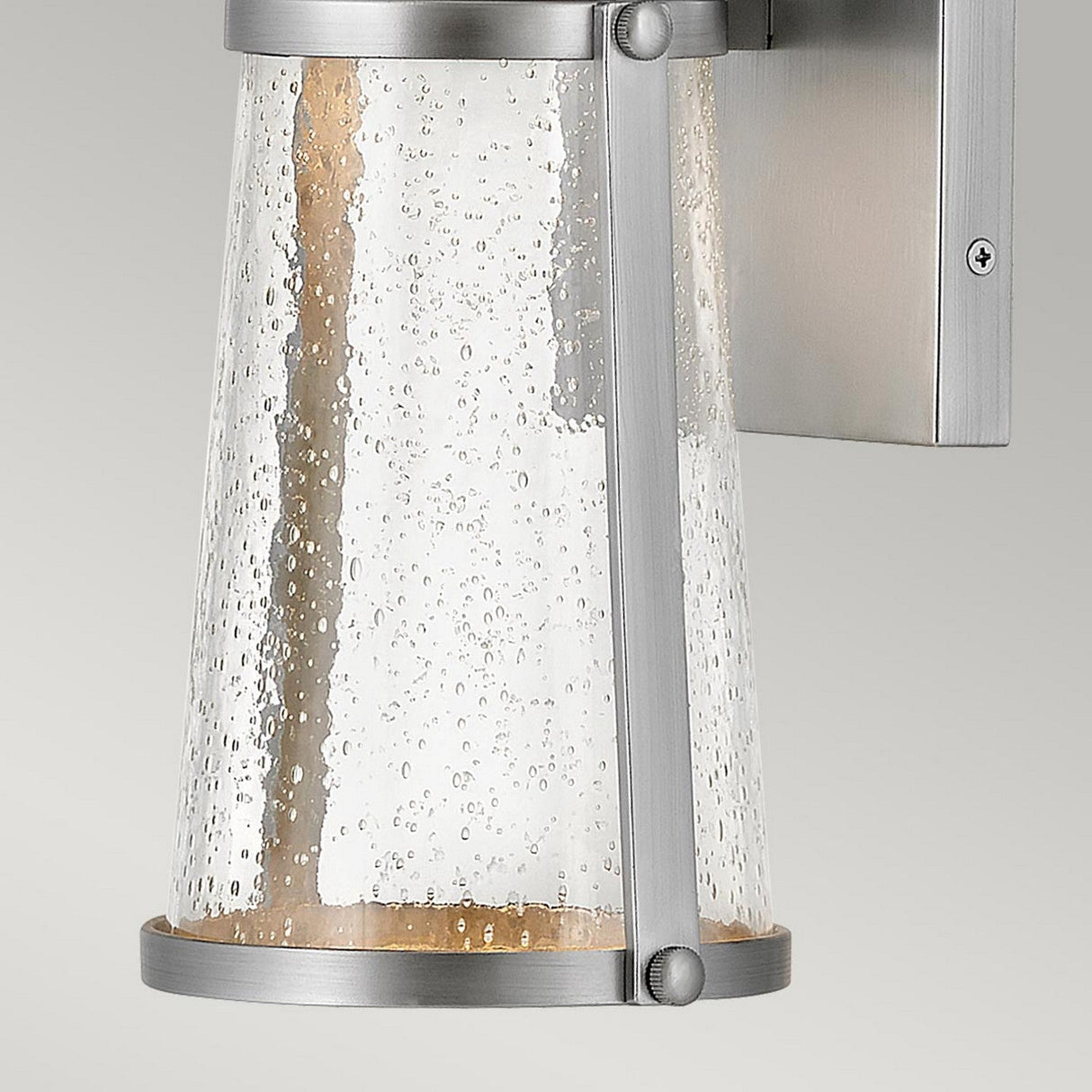 The Miles 1 Light Wall Lantern - Painted Satin Nickel features a contemporary design with a clear cylindrical glass shade adorned with delicate bubbles. Inside, an LED GU10 lamp emits a warm glow, infusing any room with nautical charm.