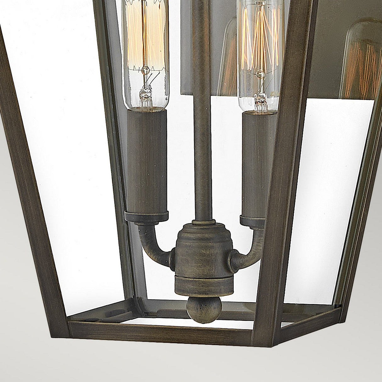 Close-up of the Palma Outdoor 2 Light Medium Wall Lantern in burnished bronze, highlighting two visible Edison bulbs. The design boasts a clear glass enclosure with a metal frame, showcasing the intricate lamp holder and bulb filaments—ideal for adding charm to outdoor decor.