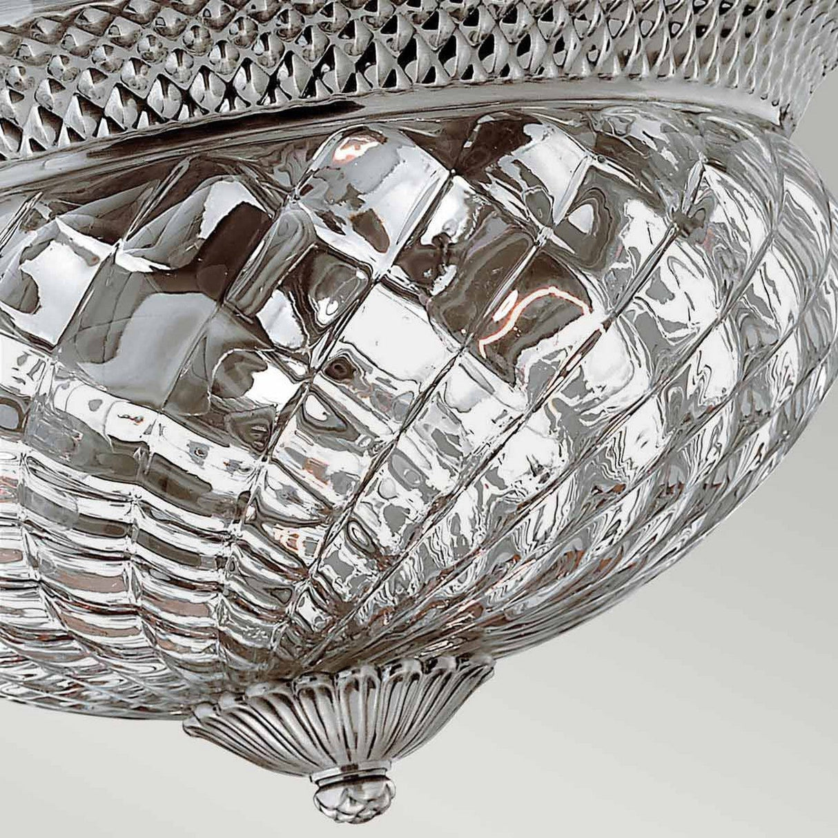 Close-up of the Plantation 3 Light Large Flush fixture, featuring an intricate, pineapple-shaped design crafted from clear optic glass with diamond-patterned details. It boasts a polished antique nickel finish, providing a shiny, elegant appearance against a plain background.
