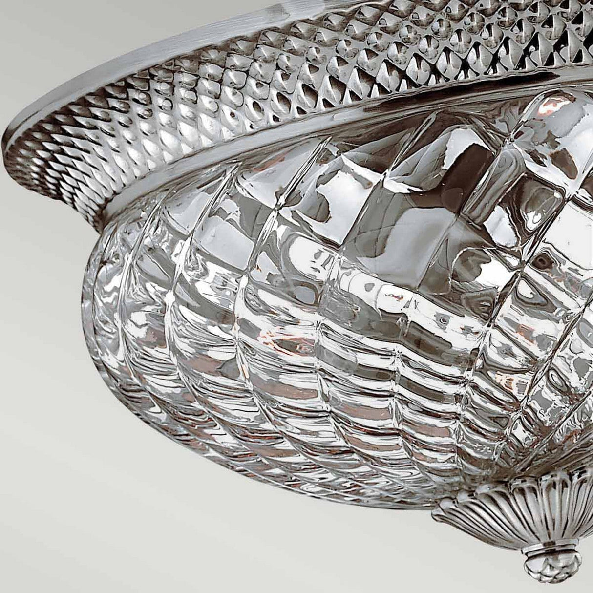 A close-up of the Plantation 3 Light Large Flush reveals its ornate ceiling light fixture featuring a glass bowl design and a textured metallic rim. With its patterned, reflective surface in polished antique nickel, it exudes an elegant and vintage appearance against a light background.