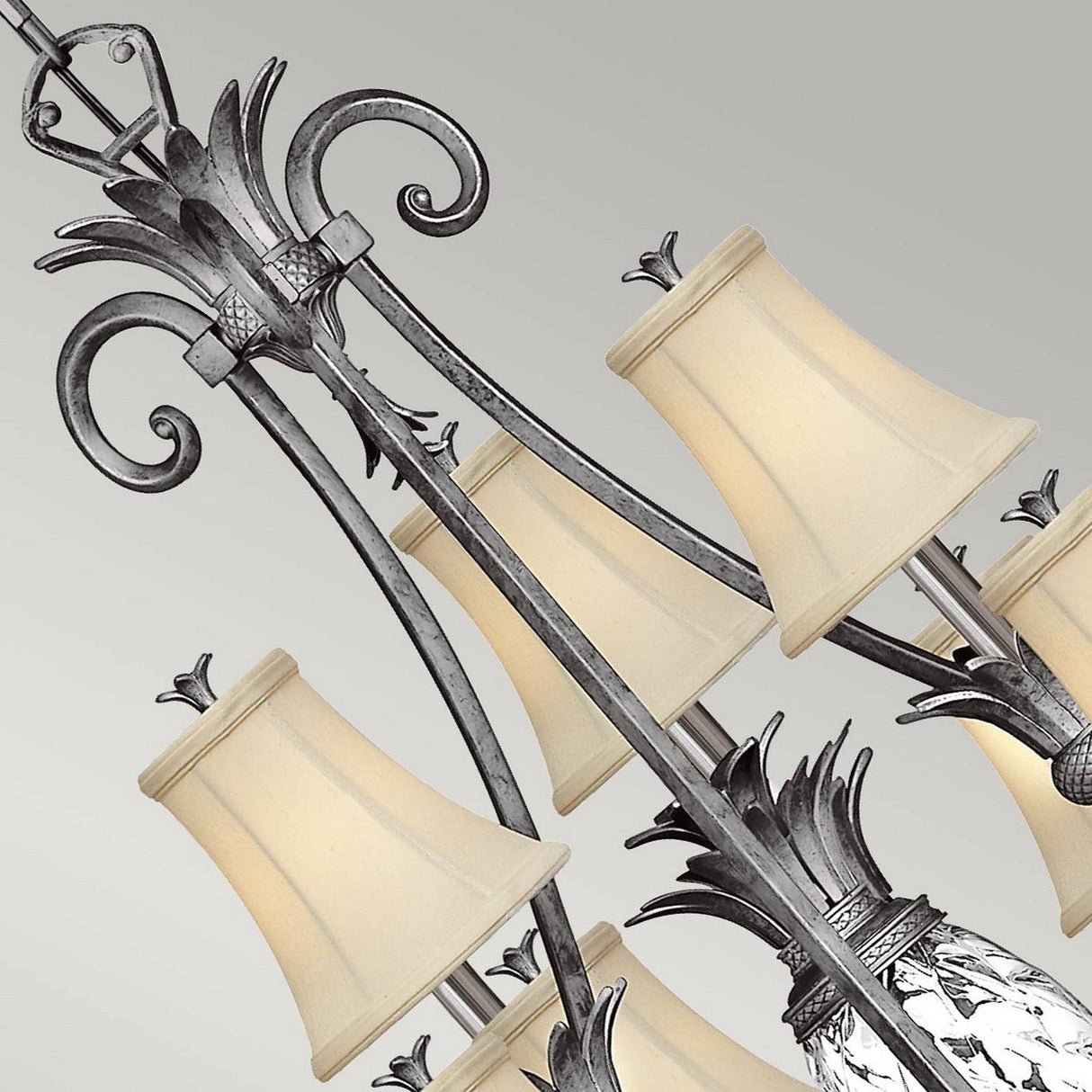 A close-up view of the Plantation 10 Light Chandelier, showcasing its ornate metallic design with a polished antique nickel finish. This chandelier features ten light fixtures adorned with decorative elements and white lampshades, offering an elegant and classic aesthetic.