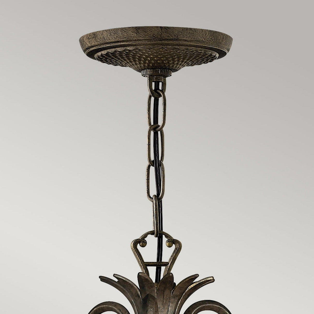 Close-up of the Plantation 3 Light Chandelier - Bronze, showcasing a decorative ceiling light fixture with a textured brass chain and clear optic glass. This piece from the Plantation collection features ornate detailing and a round ceiling mount in a Pearl Bronze finish, all set against a neutral background.