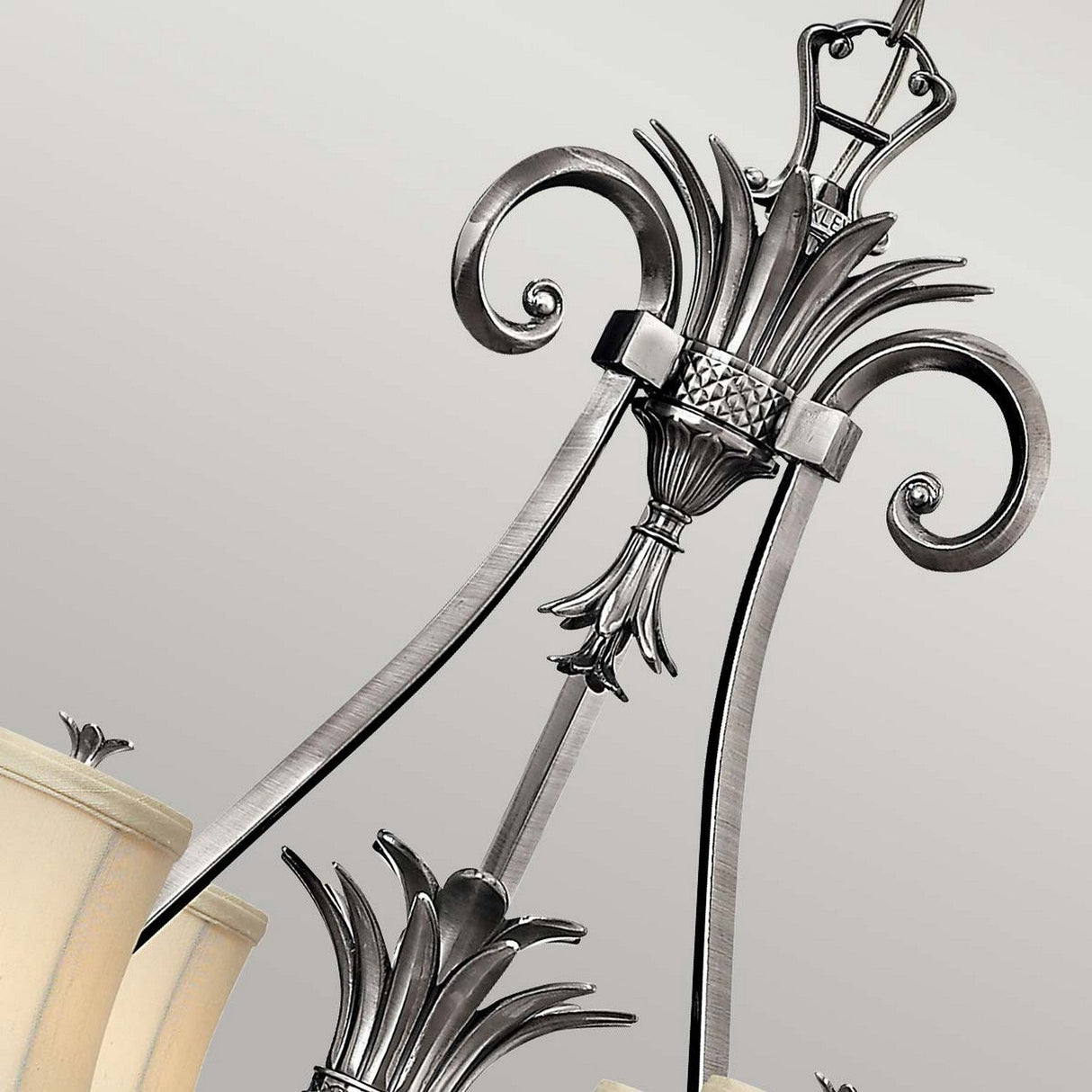 Close-up of the Plantation 7 Light Chandelier - Polished Antique Nickel, showcasing its intricate scrollwork and frosted glass shades. This design boasts elegant, curved lines and decorative clear optic glass elements shaped like pineapples, creating a classic and sophisticated look.