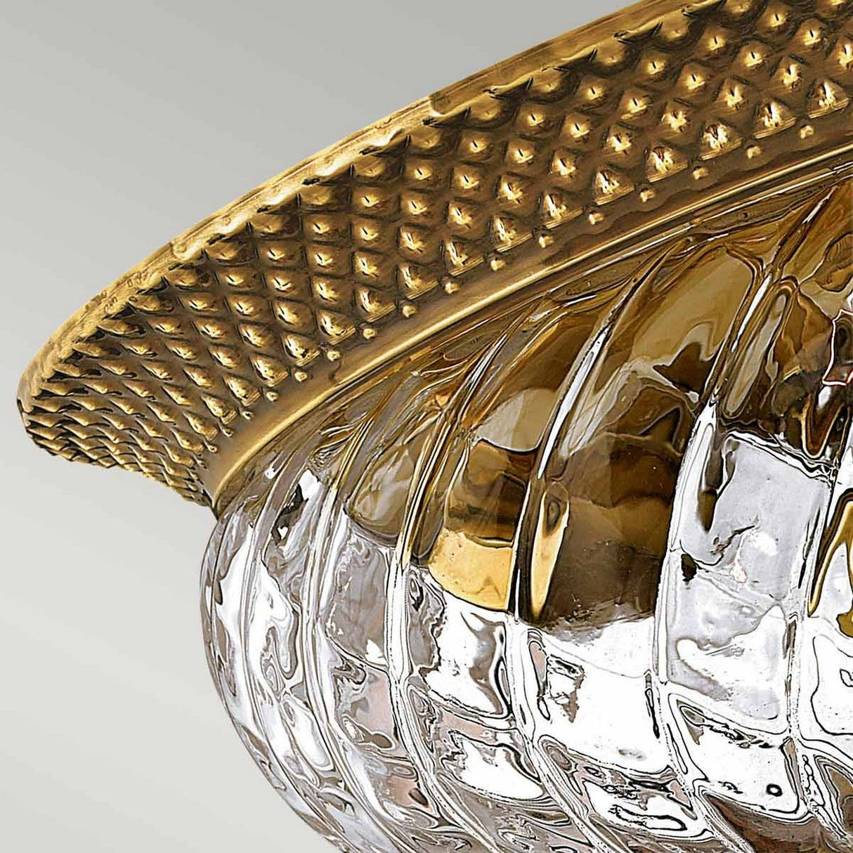 Close-up of the Plantation 2 Light Flush in burnished brass showcasing its textured golden rim and patterned glass design. The pineapple-shaped elements contribute to a luxurious and elegant appearance.