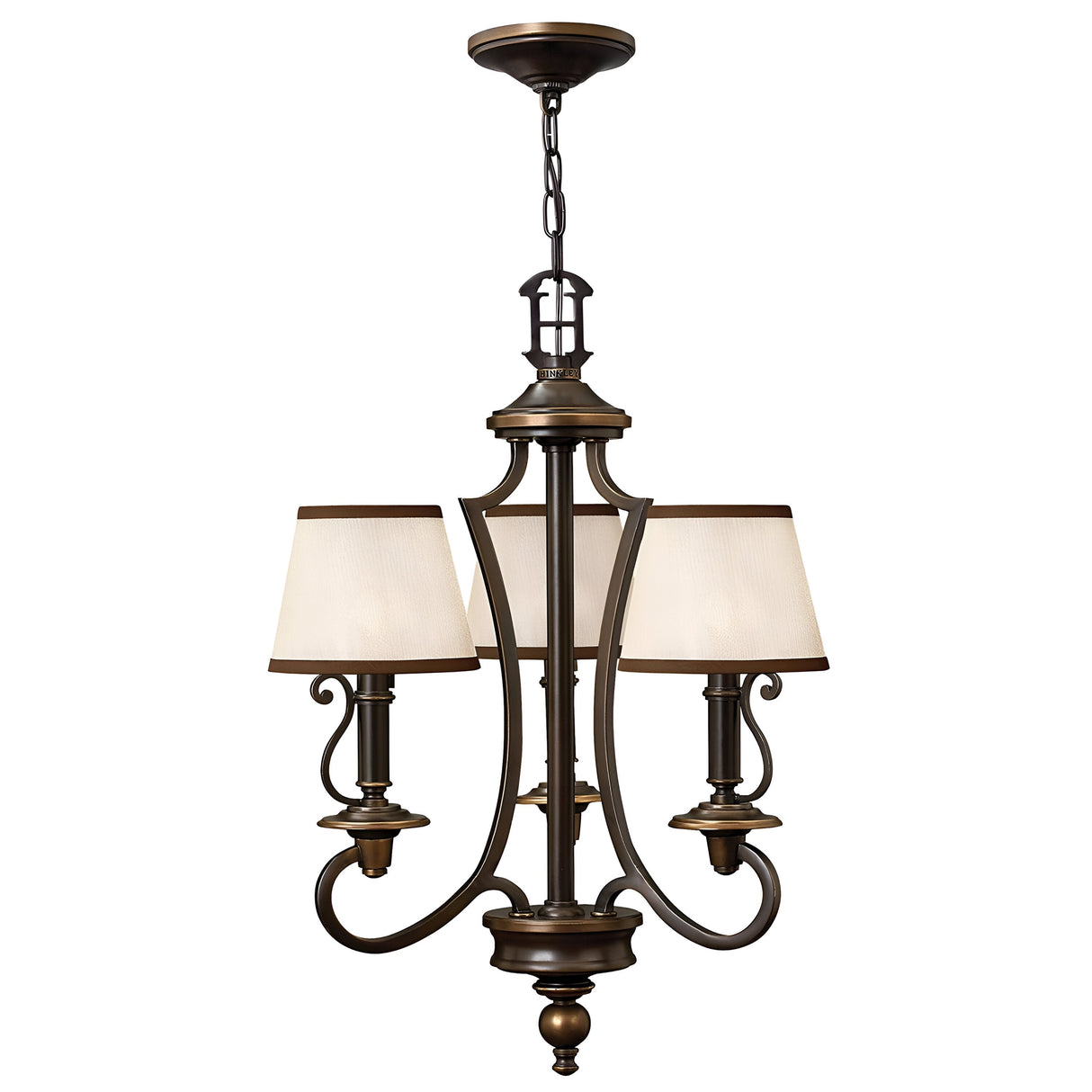 The Plymouth 3 Light Chandelier - Bronze features a vintage-inspired design with a bronze finish. It has three elegantly curved arms, each adorned with a cream-colored fabric lampshade. The chandelier includes intricate scrolling details and is gracefully suspended by a chain from the ceiling mount on its central rod.