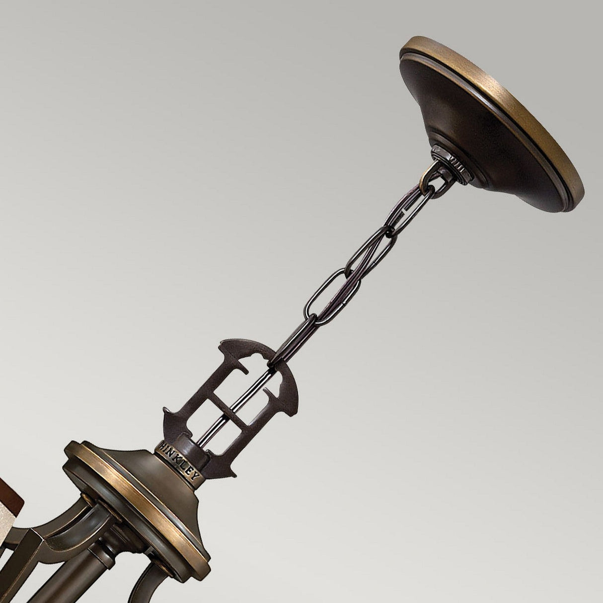 A close-up of the Plymouth 6 Light Chandelier - Bronze highlights its chain and part of the chandelier's body against a plain background, showcasing its elegant vintage charm.