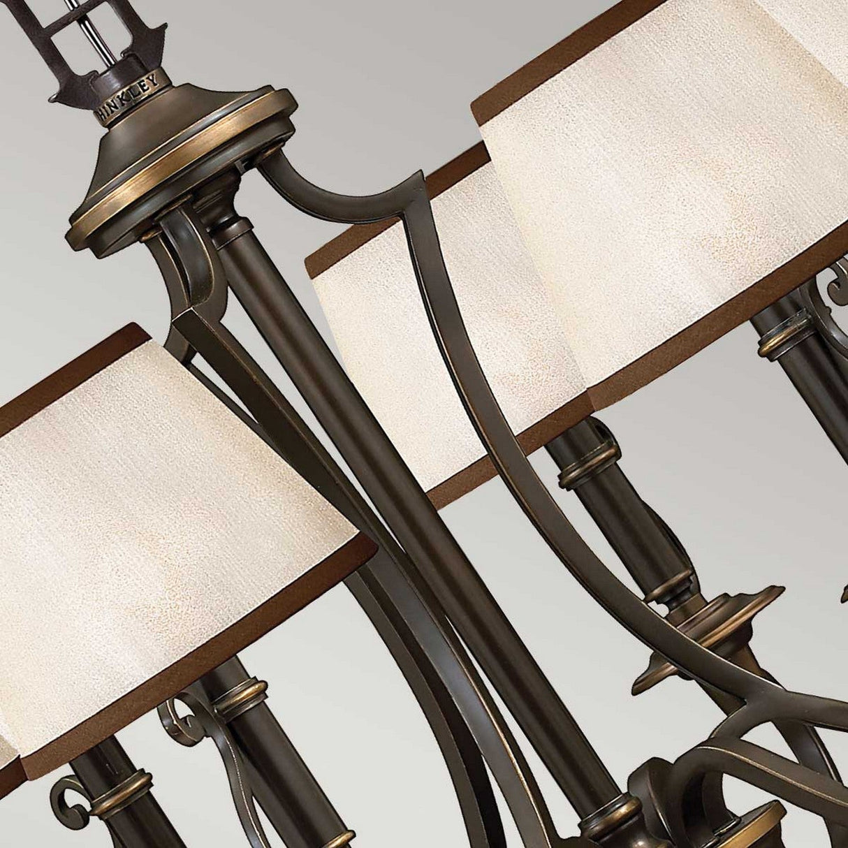 Close-up of the Plymouth 6 Light Chandelier - Bronze, exuding vintage charm with its ornate design. It features elegant curves and several square white lampshades, beautifully accentuated against a neutral background.