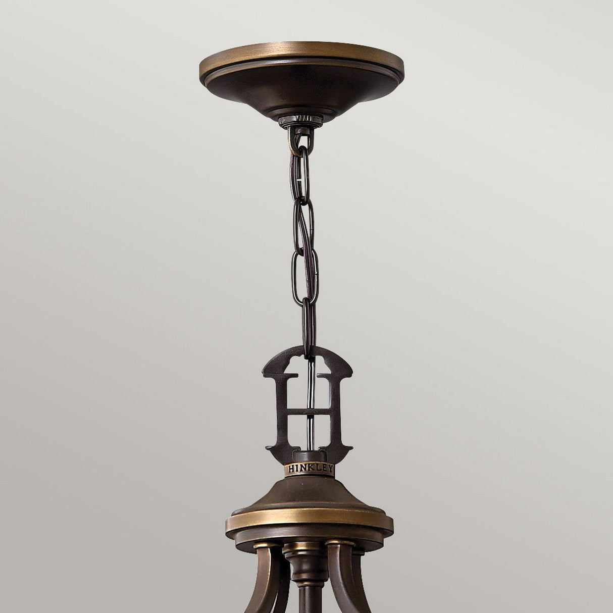 A bronze chain and mount with decorative links and a circular ceiling plate evoke timeless elegance, reminiscent of the Plymouth 8 Light Chandelier - Bronze, against a light gray background.