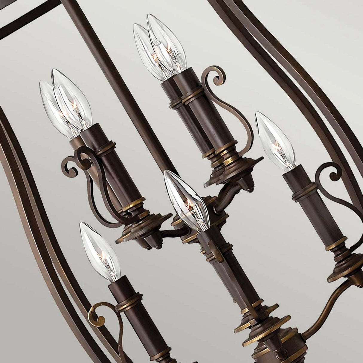 A close-up of the exquisite Plymouth 8 Light Chandelier in bronze, showcasing eight candle-style light bulbs. The design highlights ornate curves and intricate metalwork, accentuated by vintage candle sleeves for a classic and sophisticated look.