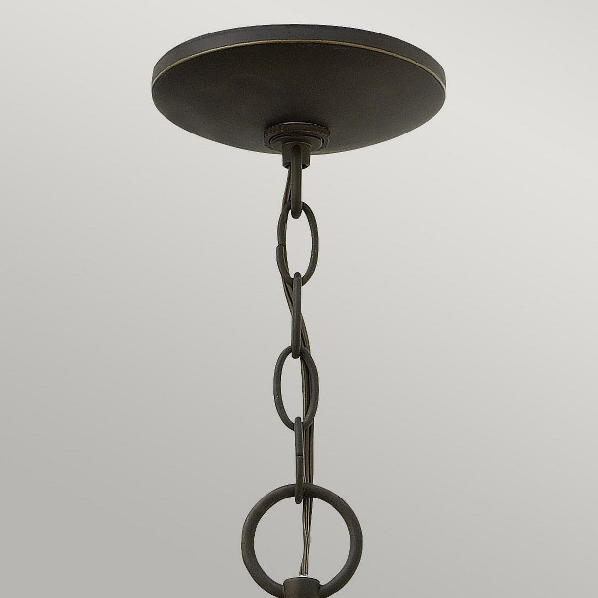 Close-up of the Quincy Outdoor Medium Chain Pendant, featuring an oil-rubbed bronze finish with interlinked metal rings hanging from a round, dark metal base. The background is a plain, light gray.