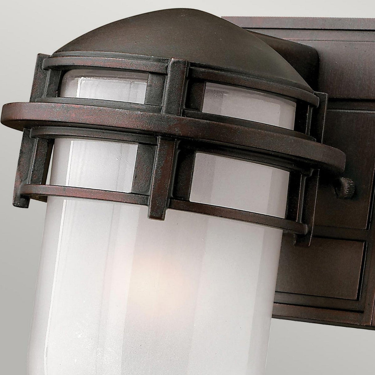 A close-up view of the Reef Mini Outdoor 1 Light Lantern - Bronze, crafted from cast aluminum with a frosted glass shade and dark bronze housing. This lantern features a modern yet classic design, emitting a soft glow perfect for an IP44-rated outdoor setting.