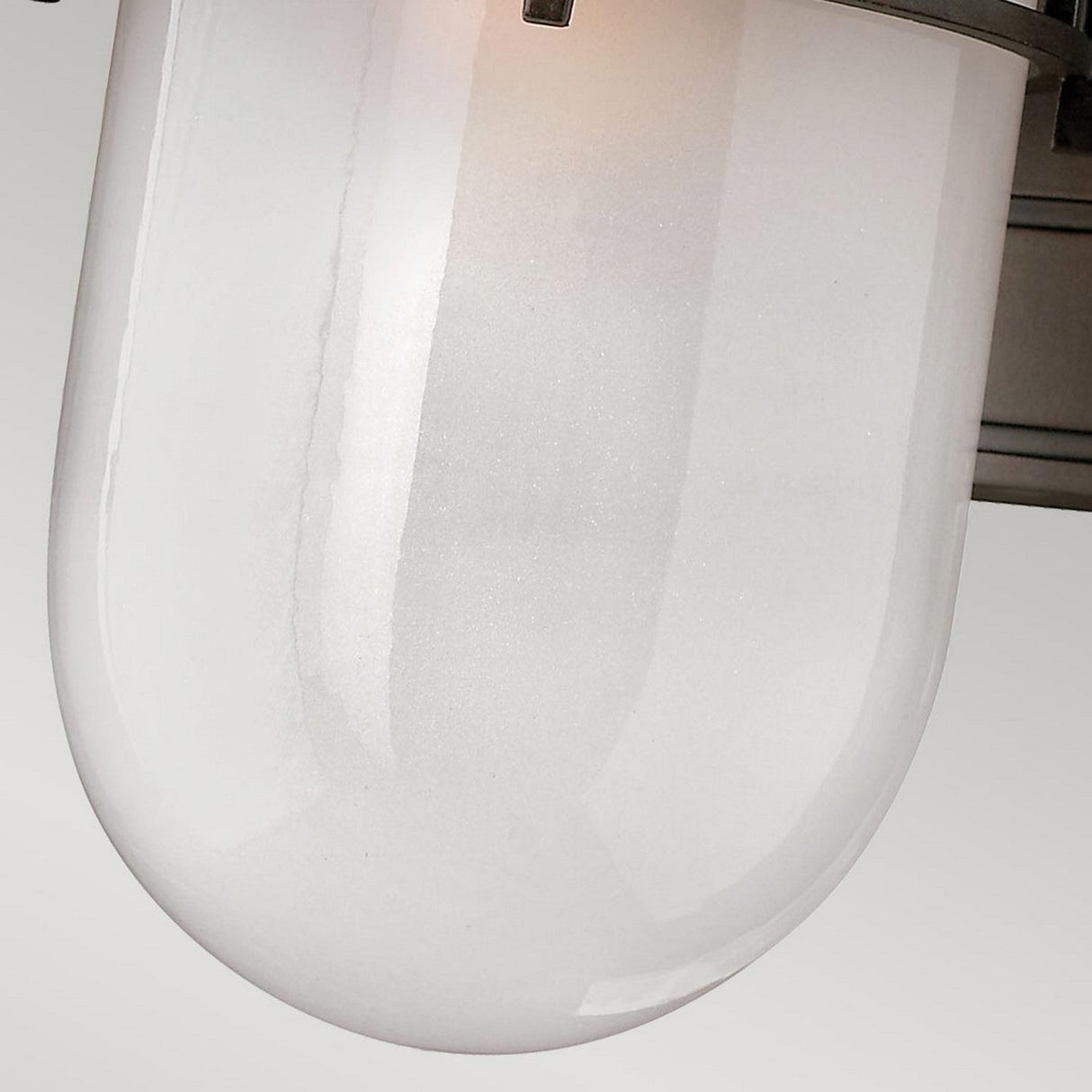 Close-up of the Reef Outdoor Small 1 Light Lantern in a modern, translucent white glass design with a smooth, rounded shape, set against a plain background. The lantern, featuring an IP44 rating for outdoor use, is secured to a bronze metallic support.