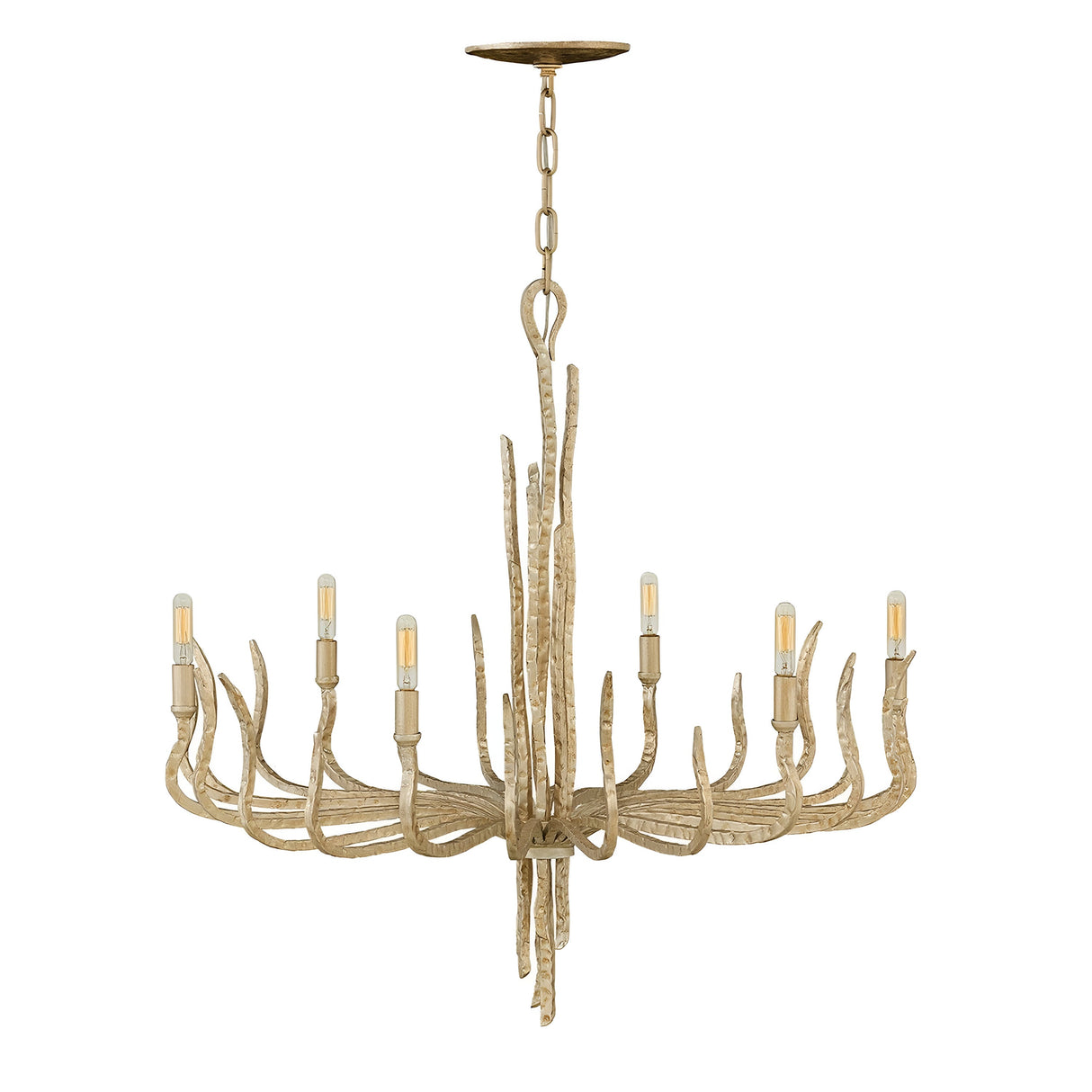 A Spyre 6 Light Chandelier in the Champagne Gold finish hangs from the ceiling with a rustic antler design. It features six light bulbs arranged in a circular pattern, emitting a warm glow. The chandelier has a natural, wood-like appearance accented with elegant Champagne Gold touches.