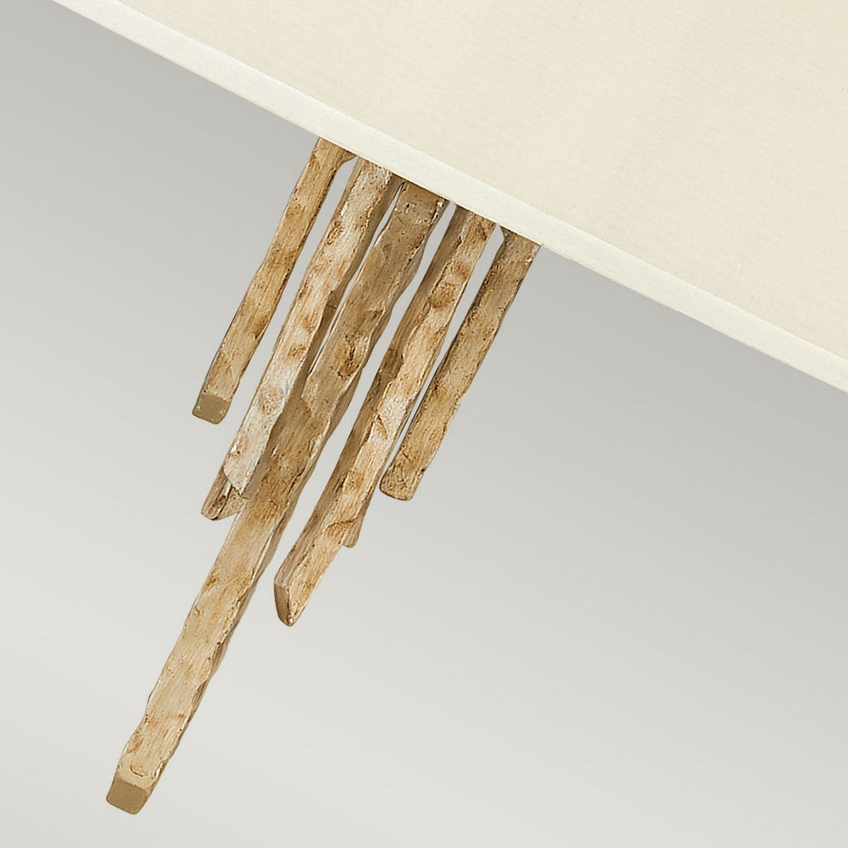 Close-up of the Spyre 6 Light Pendant in Champagne Gold, showcasing its modern design with wooden sticks partially embedded in a flat, light-colored surface. The textured sticks offer a striking contrast against the smooth background, making it versatile for various decor styles.