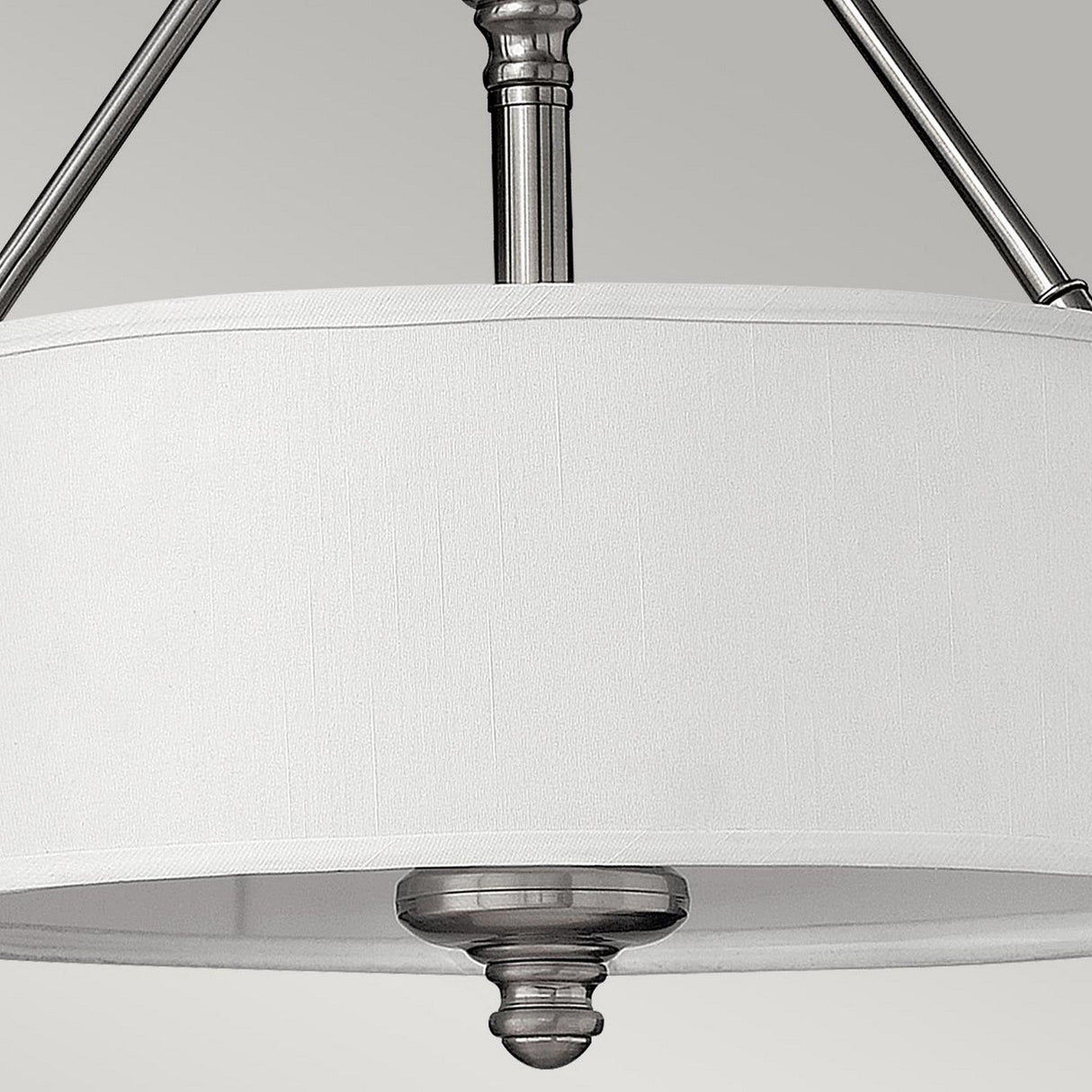 A close-up of the Sussex 3 Light Semi Flush in Brushed Nickel, featuring a drum-shaped fabric shade in white and brushed nickel accents, set against a light gray background. The fixture combines traditional modern lighting elements with a contemporary, elegant design.