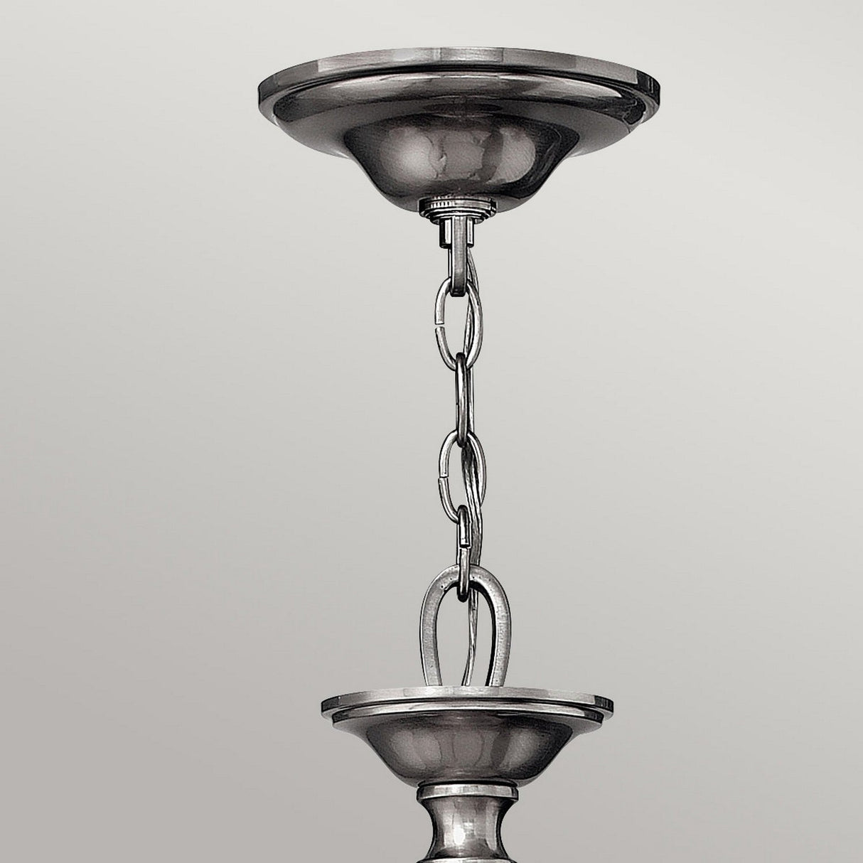 Close-up of a metallic hanging chain secured to two circular ceiling fixtures with a smooth, reflective surface, highlighting the classic appeal of the Sussex 5 Light Chandelier - Brushed Nickel. Its finish offers an elegant contrast against the neutral, light gray background.