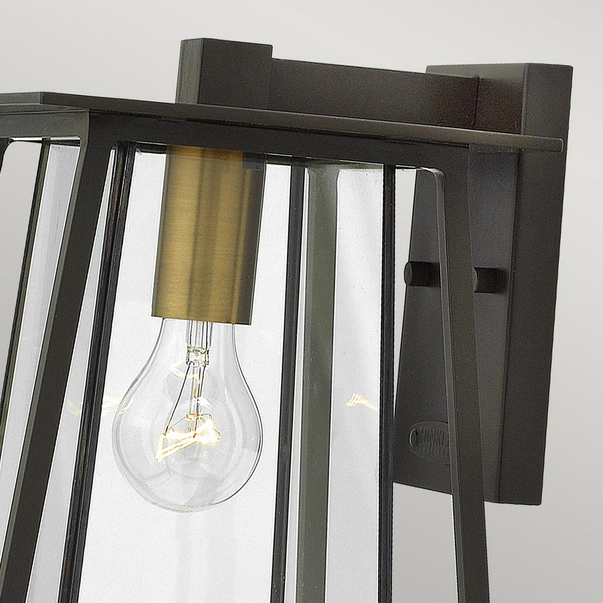 The Walker Outdoor 1 Light Medium Wall Lantern showcases a clear glass cover and exposed light bulb, ideal for rustic decor. It features a dark bronze frame and a heritage brass socket, set against a light gray background.