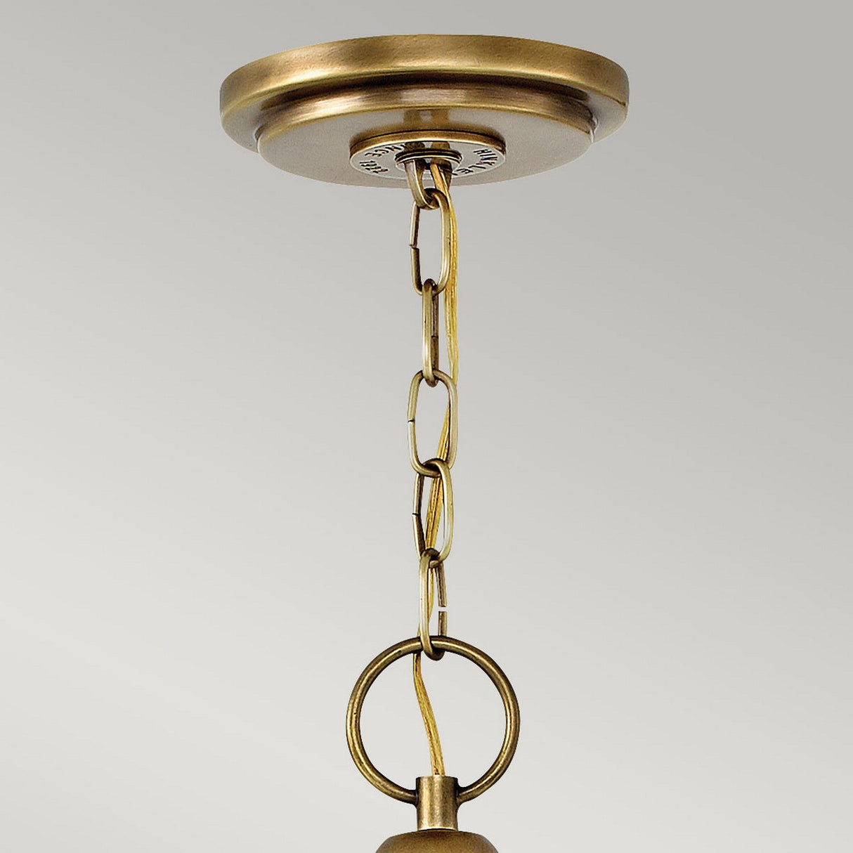 A close-up of the Wexley 5 Light Chandelier in Heritage Brass, showcasing vintage-inspired elegance with its chain-linked circular fixture against a plain gray background.