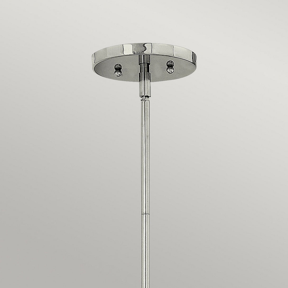 Introducing the Zelda 1 Light Mini Pendant in Polished Nickel, a minimalist chrome ceiling mount featuring a sleek cylindrical rod that embodies mid-century elegance. It extends gracefully downward, beautifully contrasting against a plain gray background.