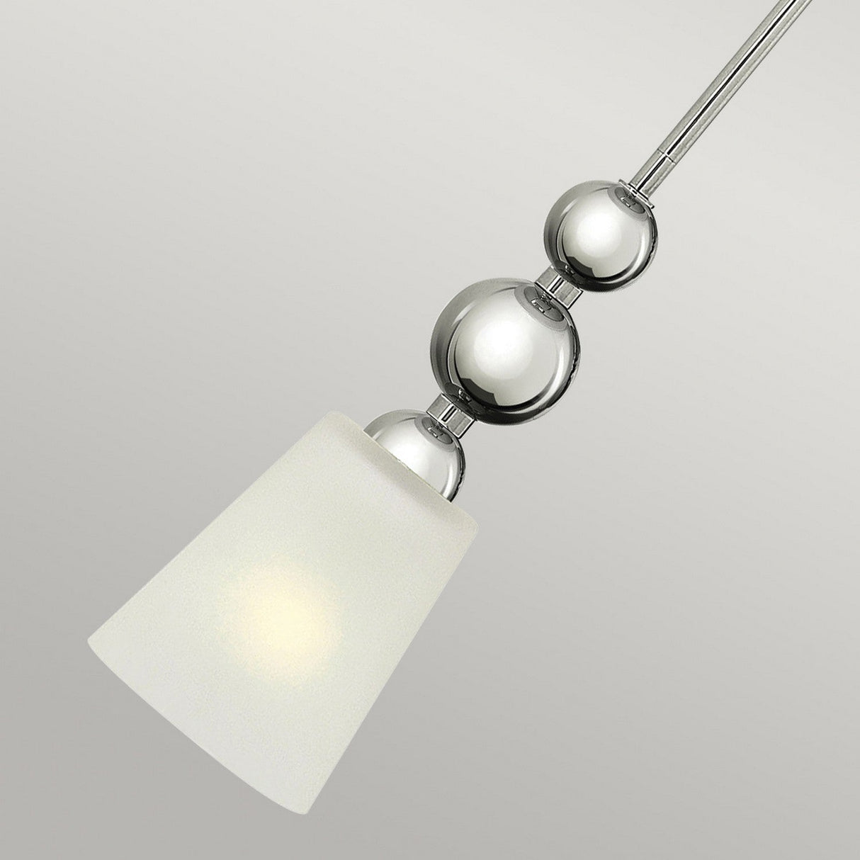 Close-up of the Zelda 1 Light Mini Pendant in a polished nickel finish. This contemporary fixture highlights mid-century elegance with three glossy, spherical components stacked vertically and a conical white glass shade, all set against a simple, neutral backdrop.