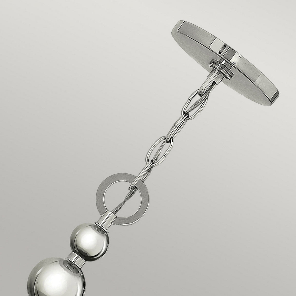 A close-up of the Zelda 3 Light Pendant - Polished Nickel highlights its modern chain-link design. The fixture features a polished nickel finish, complete with a circular plate at the top and two spherical elements along the hanging chain, all of which contribute to its sleek, mid-century charm.