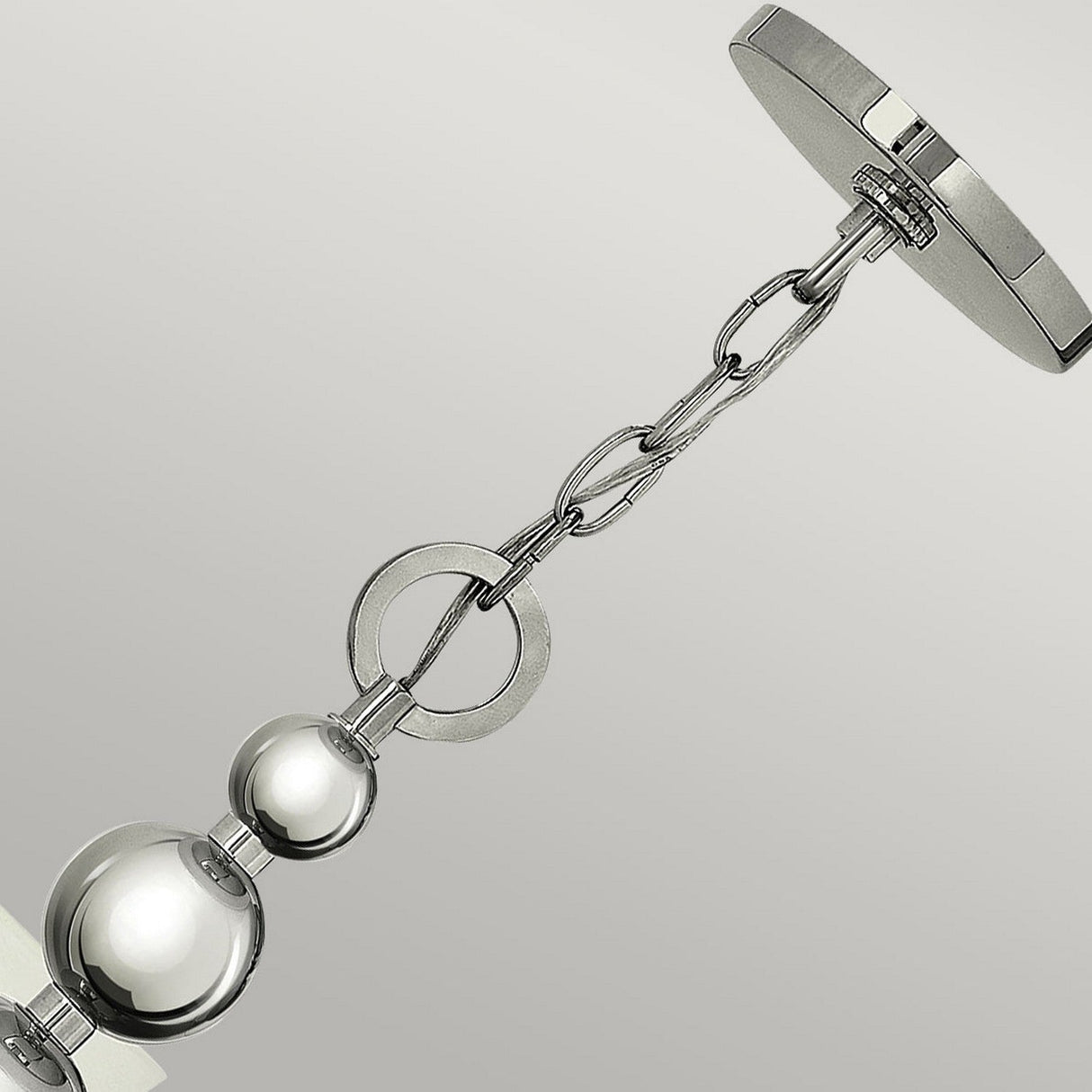 An up-close view of the Zelda 5 Light Chandelier - Polished Nickel showcases its mid-century elegance. This metallic pendant light features a chic chain link design adorned with polished nickel spheres and rings, suspended gracefully from a sleek ceiling mount set against a light gray backdrop.