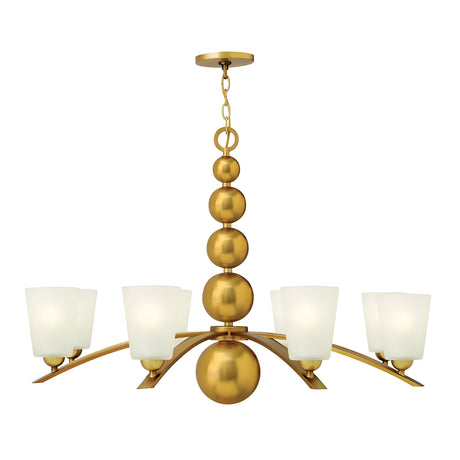 The Zelda 8 Light Chandelier in Vintage Brass showcases a mid-century design with five frosted glass lampshades encircling a central structure of stacked spheres. It is suspended by a chain, offering a sleek and elegant appearance.